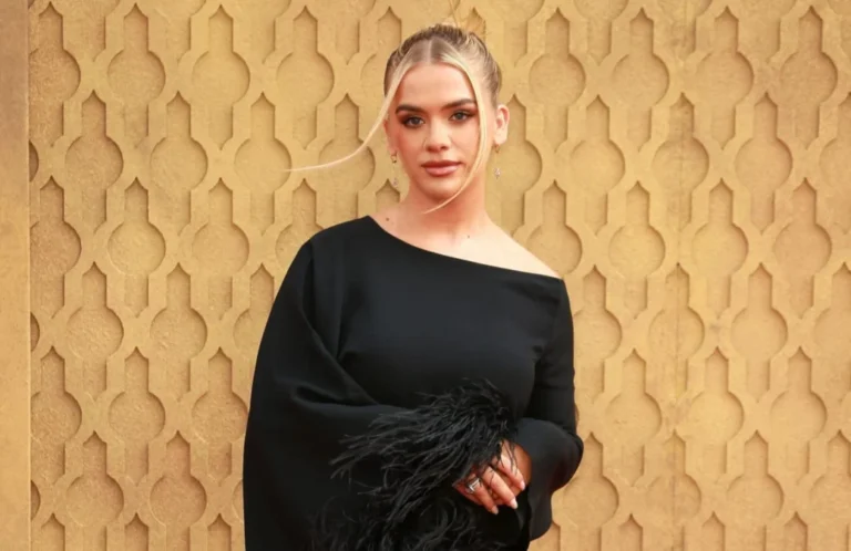 Grace Beverley, founder of Tala, posing in a stylish black dress with feather detailing, against a decorative gold patterned background. Her blonde hair is pulled back, and she looks directly at the viewer.