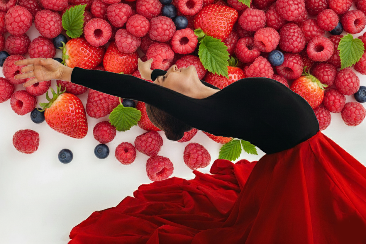 Woman in a flowing, voluminous red skirt and black top gracefully arching her back beneath a lush apple tree laden with bright red fruit in a sun-dappled garden.