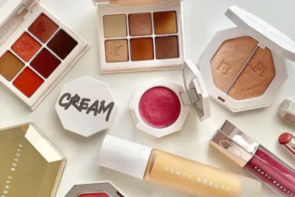 Fenty Beauty makeup products including foundation and highlighters displayed on a vanity table, representing the inclusive beauty brand co-founded by Rihanna.