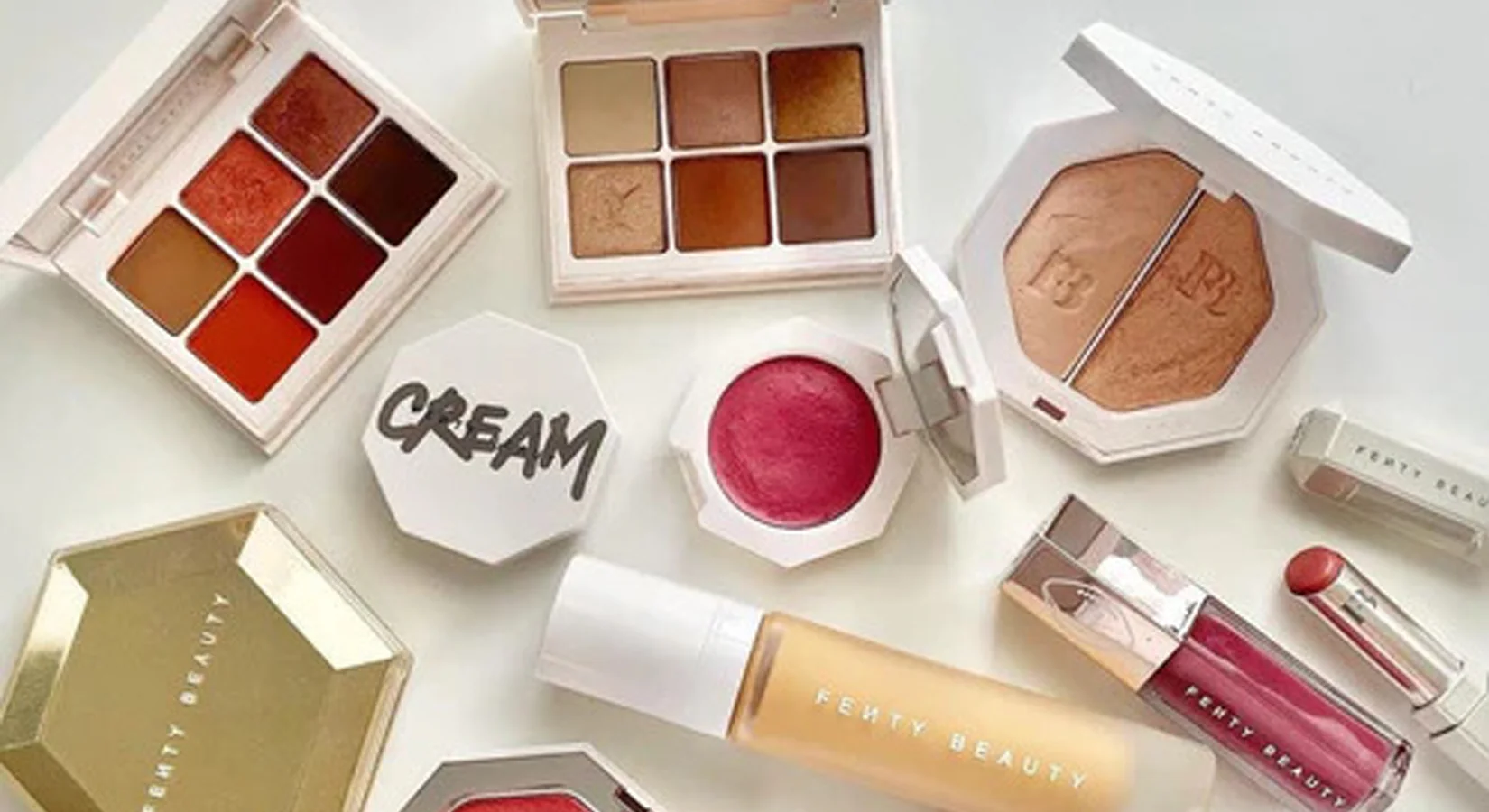 Fenty Beauty makeup products including foundation and highlighters displayed on a vanity table, representing the inclusive beauty brand co-founded by Rihanna.