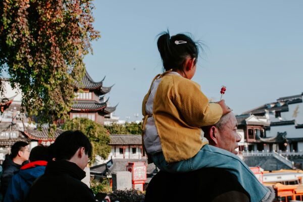 Shoppers walking past fashion retail stores in a Chinese city, reflecting the impact of population decline on consumer demand.