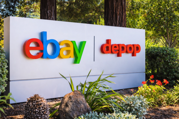 eBay and Depop logos displayed side by side on outdoor corporate signage surrounded by greenery.